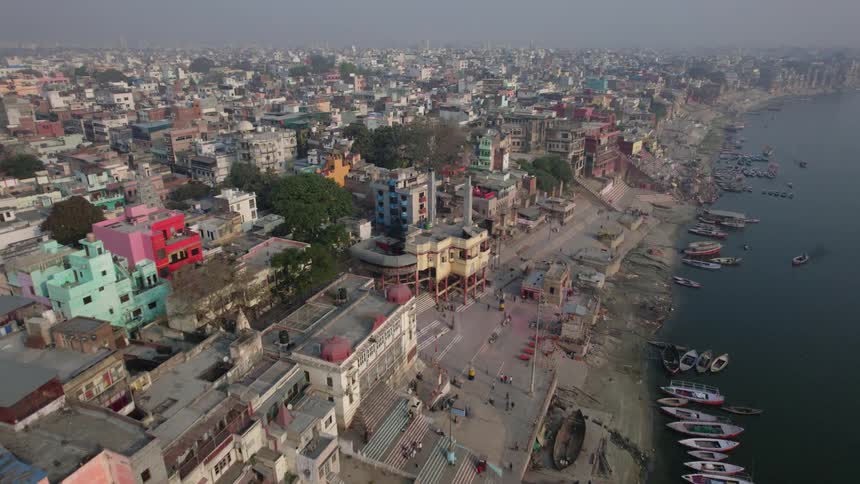A dirt pier on a coastal third world city with several small boats docked