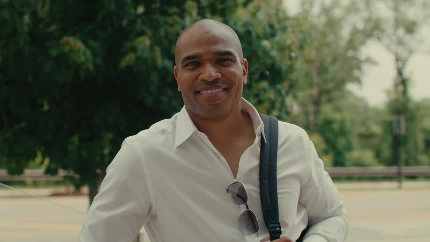 The man is smiling outside directly to camera