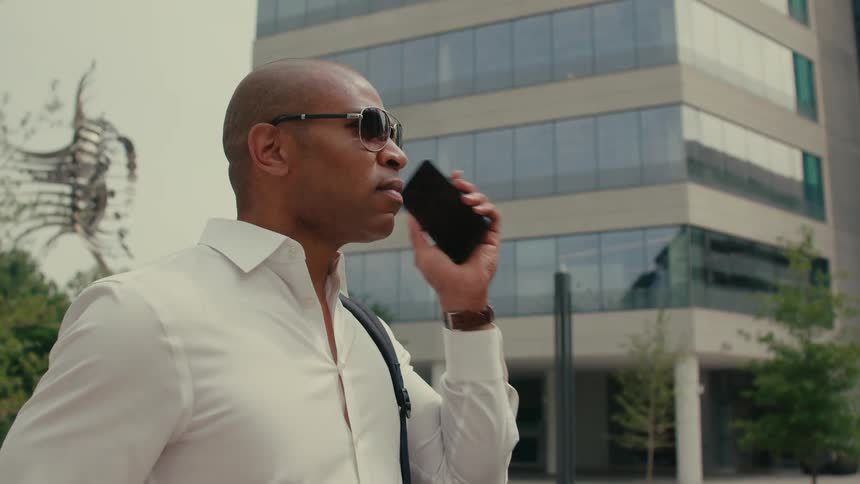 A man talks on the phone while standing downtown