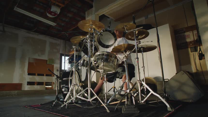 A man plays the drums in the garage