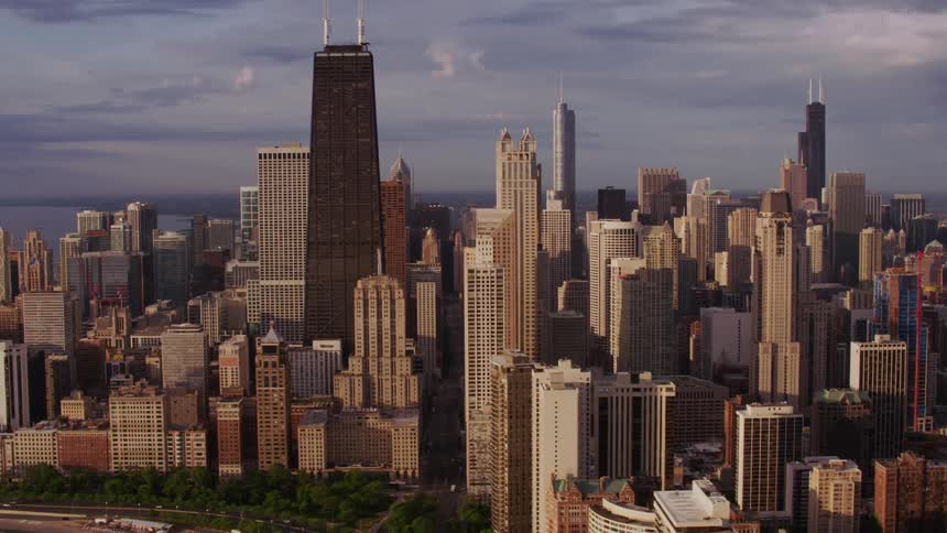 An aerial view of a huge city is shown with buildings all over and a lake right next to it