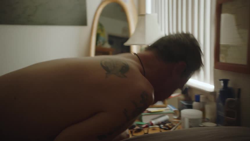 A disabled man uses his mouth to retrieve items off his bed