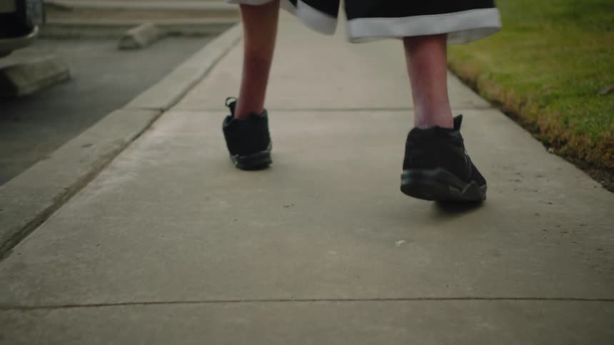 A man limps while walking down the sidewalk in an apartment complex