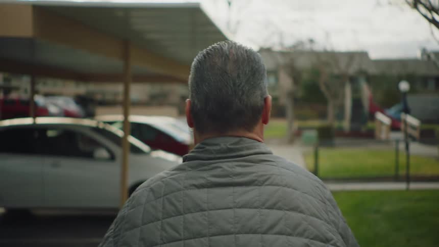 Disabled man with gray coat walks in the parking lot