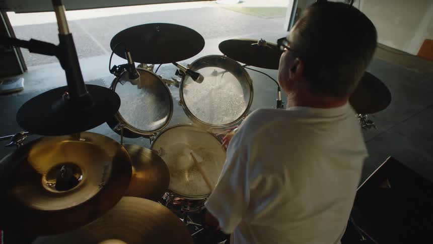 Disabled man with glasses and white t shirt plays drums