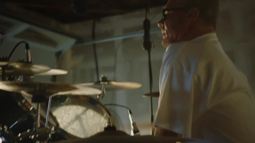 A man sitting while playing the drum set in front of him