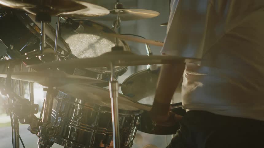 A man with a hand disability plays the drums like a pro in a basement
