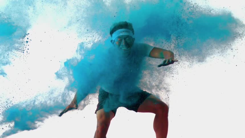 A man jumping as blue powder explodes around him