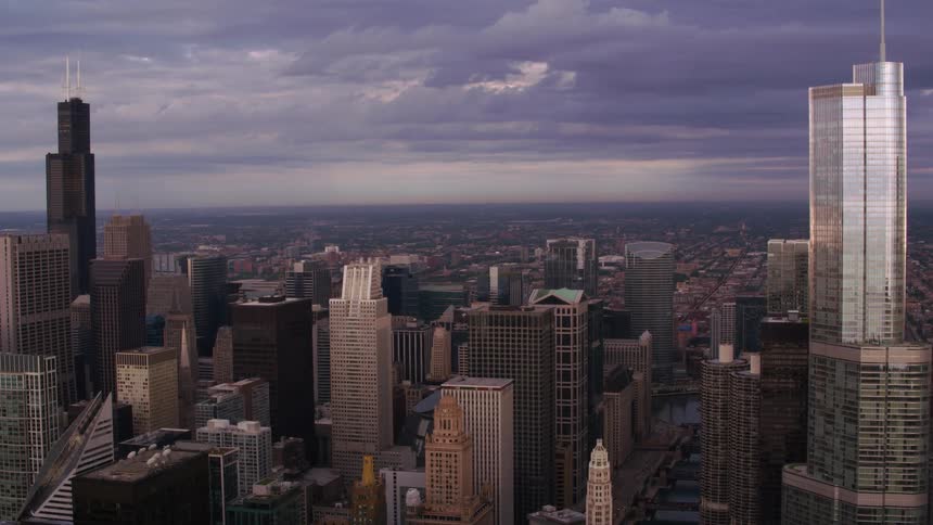 Skyscrapers and tall buildings loom over a metropolis on a cloudy evening