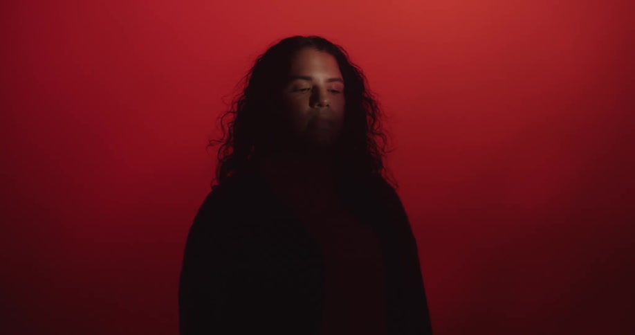 Silhouette of a woman standing with red light in the background and a light shines on her face