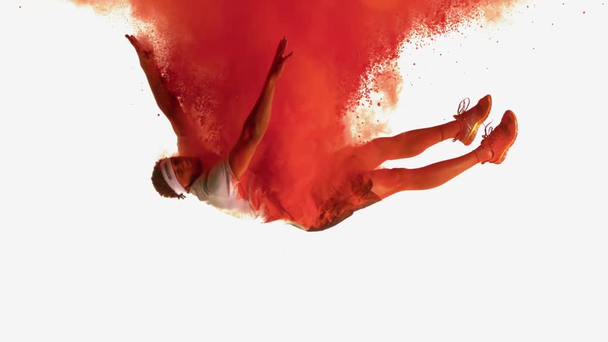 An African American athlete falling through a cloud of red powder