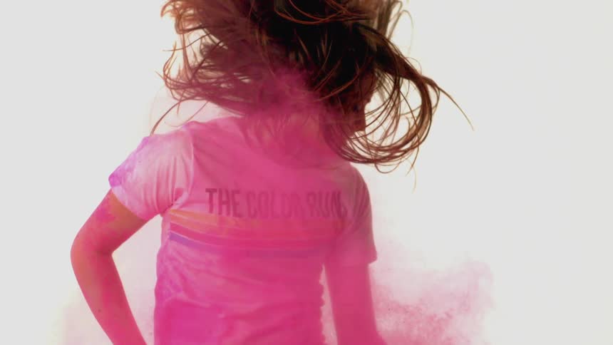 A woman falls in slow motion through pink colored powder