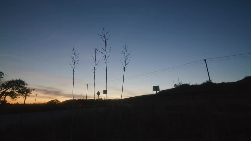 A car drives down a rural highway at sunset