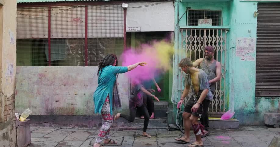 Friends throw colored holi powder at each other