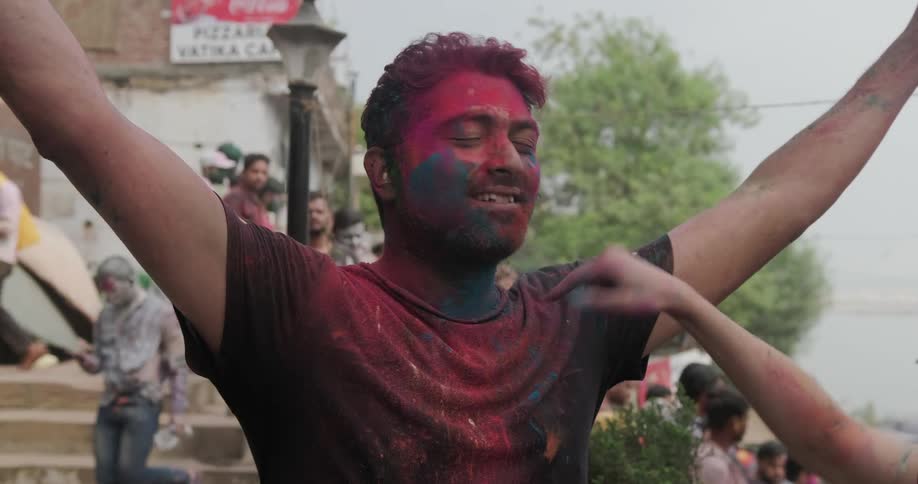 Person applies colored powder to a man as he smiles during holi