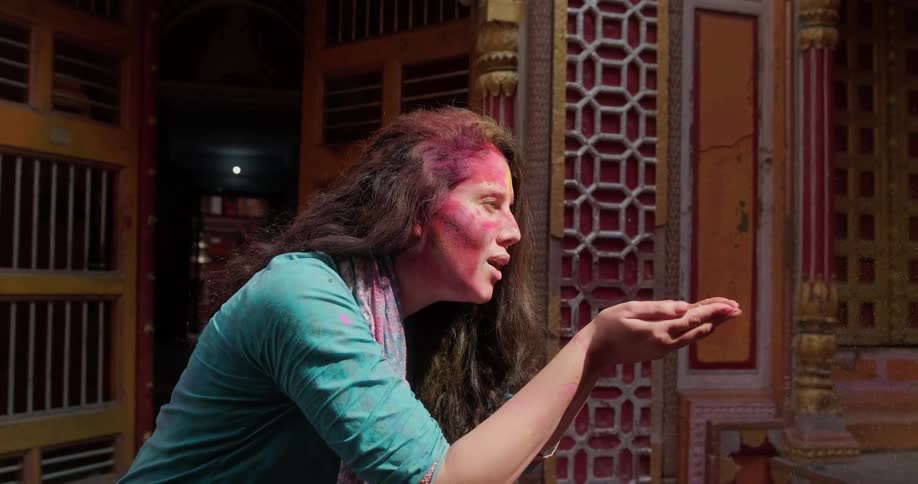 A woman blows colored dust out of her hands