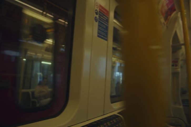 Two lightly occupied tube trains pass each other at the station