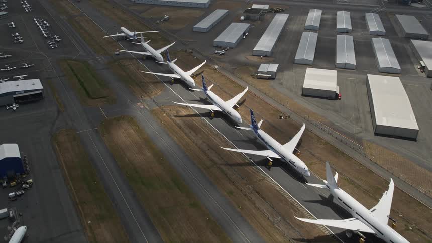 Approach and fly over a row of parked airliners at Paine Field in Washington state during the daytime