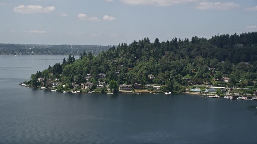Aerial footage of lakefront homes with small docks in Mercer Island Washington on a partly cloudy day