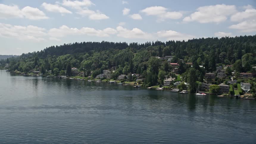 Aerial footage of lakeside homes with docks on Lake Washington in Mercer Island Washington on a partly cloudy day in the Pacific Northwest