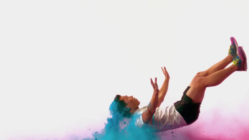 A man flies in slow motion through blue colored powder