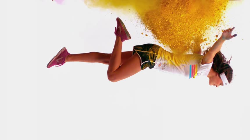 Female athlete falling through a cloud of yellow powder