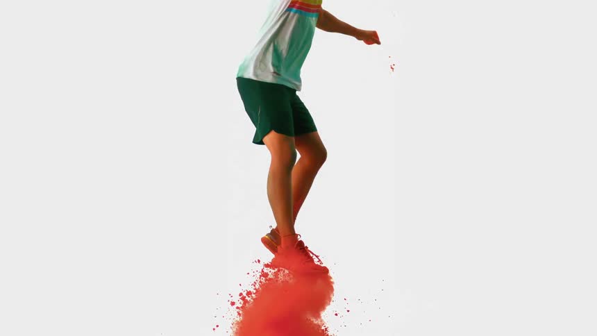 An athlete jumping into the air as a cloud of red powder erupts beneath him