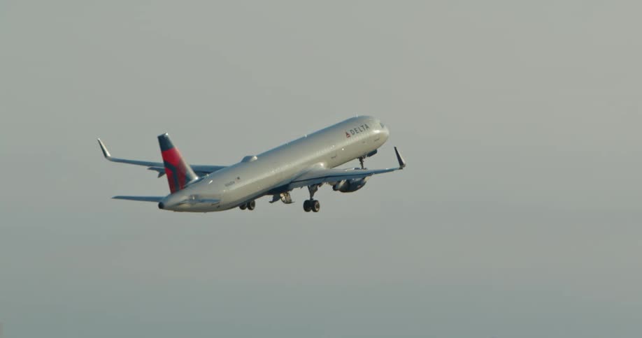 An airplane takes off with airport buildings in the distance