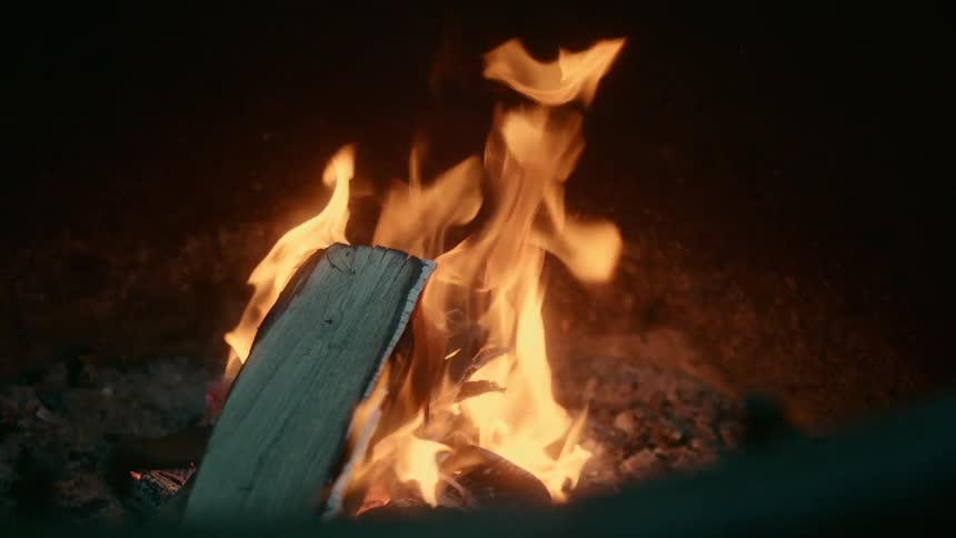 Small bonfire burning at night as the flames dance back and forth