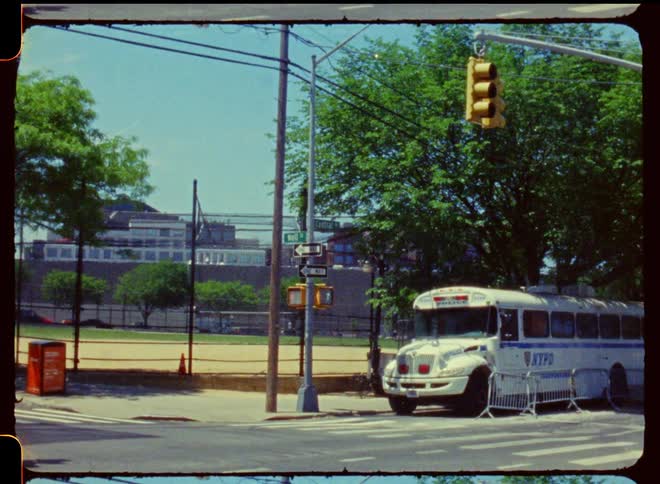 A white police bus parked in a street corner under a tree