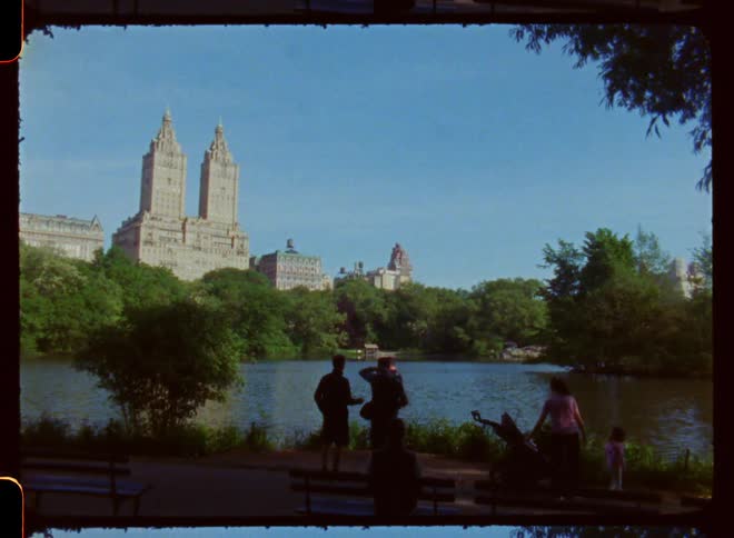 People standing near a small body of water near tall buildings and a city