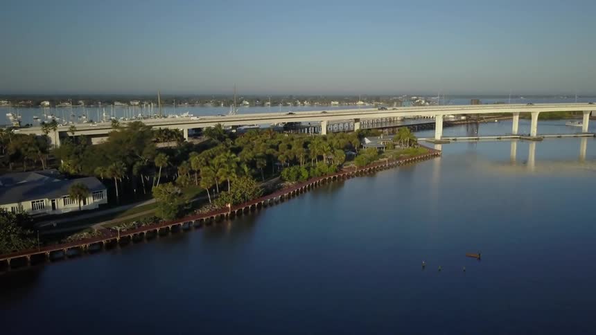 Vehicles drive over a bridge near a seaside community
