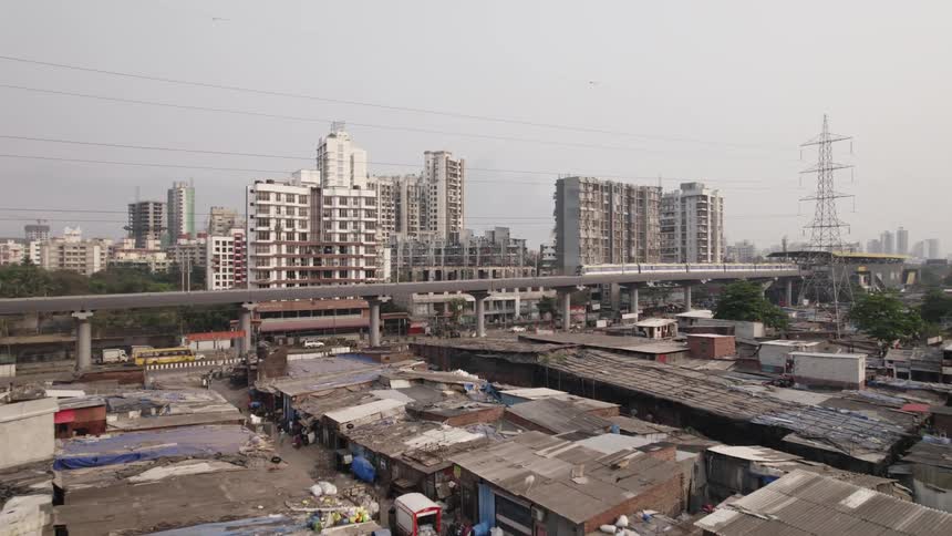 Busy road and elevated rail separate apartment buildings from slum shacks