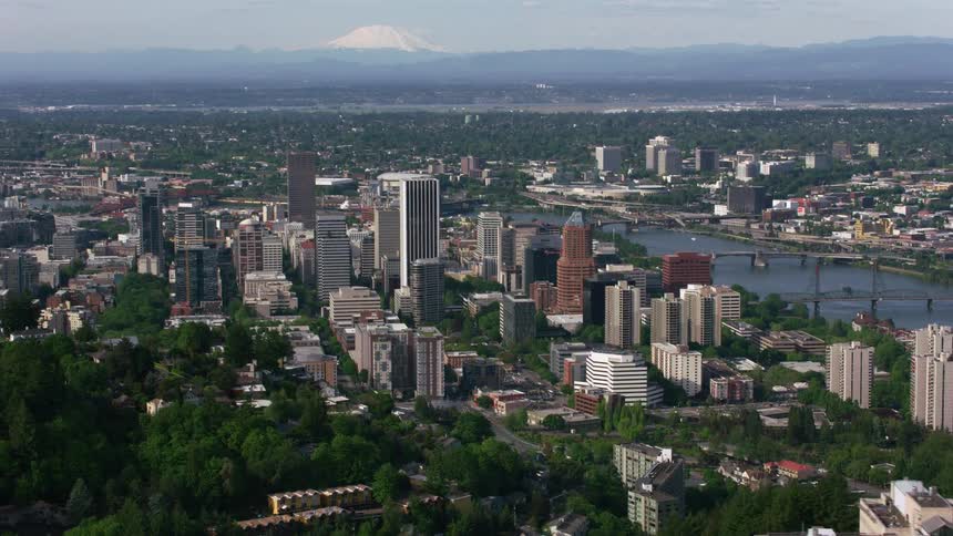 Bridges cross river between downtown and residential neighborhoods with misty snow capped mountain in the background