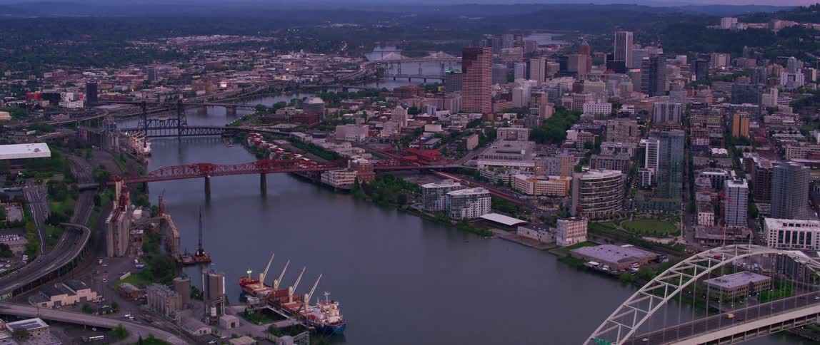 The view is of the downtown area and you can see cars driving down a bridge