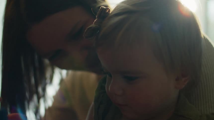 Mother with sweater holds toddler daughter smiling