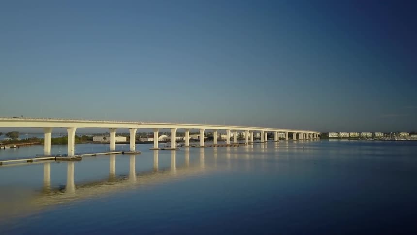 A large bridge spans a calm body of water