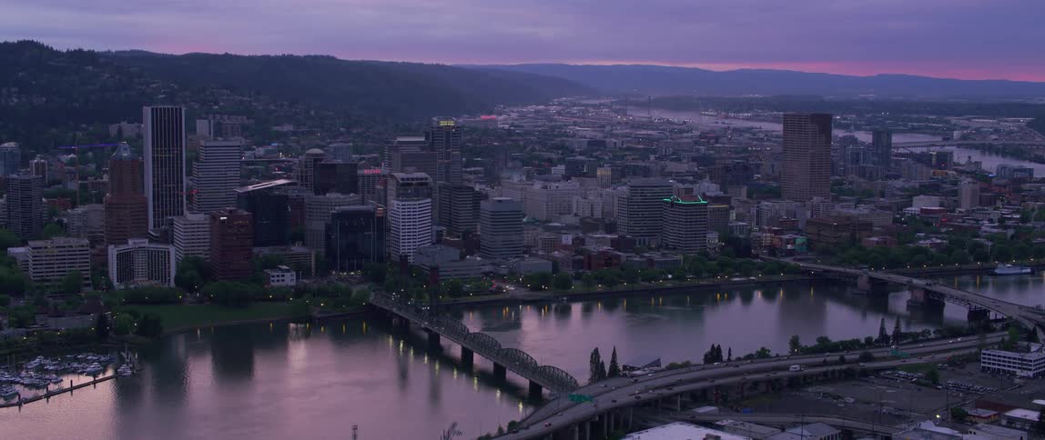 A city by a river at dawn with three bridges over the river connecting to the other margin