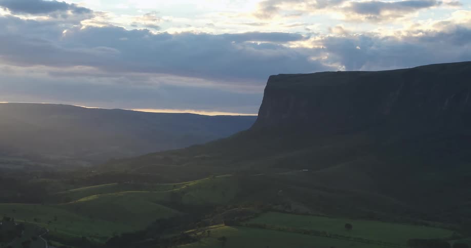Green grass grows in the valley of a steep canyon at dawn