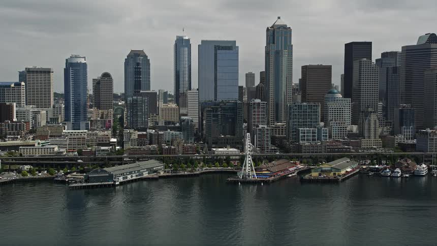 Approaching the Seattle Aquarium and Great Wheel with the Downtown Seattle skyline in the background on a cloudy day in Washingtons bustling harbor
