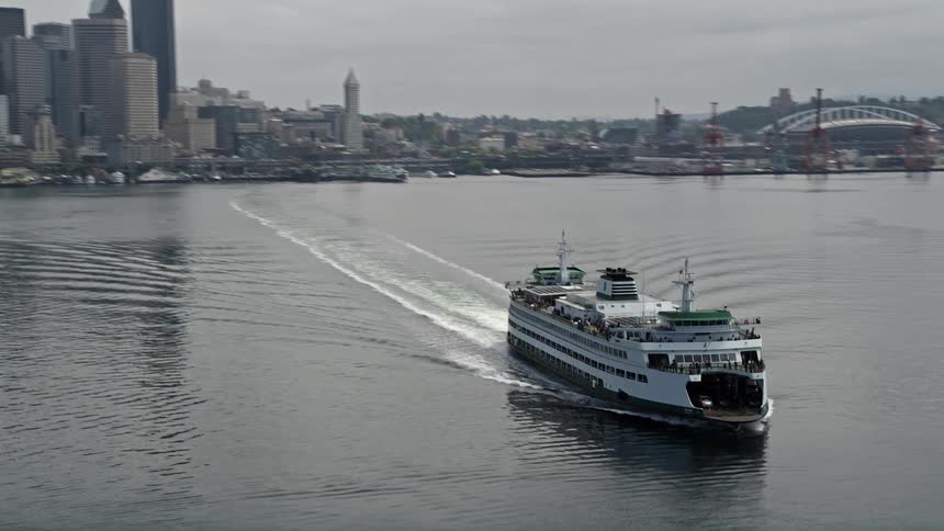 A ferry sailing away from Downtown Seattle skyline Washingtons Puget Sound in an overcast spring day