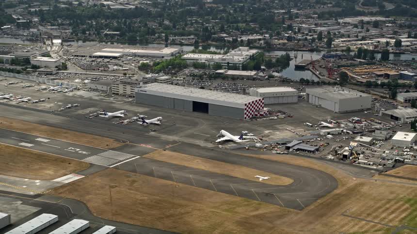 Aerial footage of a smaller plane landing on the tarmac as airliners parked by a hangar and other aircrafts are visible in the background at Boeing Field in Seattle Washington
