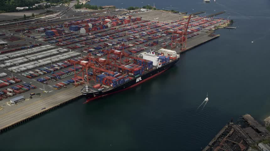 Approaching cargo ship loading containers at Port of Seattle with a aerial view during a cloudy daytime