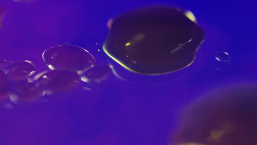 Purple bubbles flowing and crashing into each other in blue liquid
