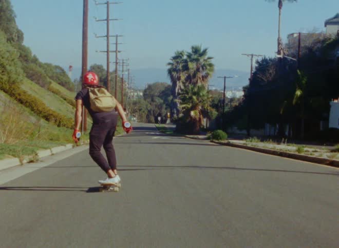 A skateboarder slaloms down a street