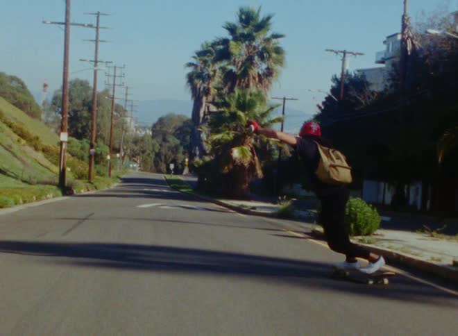 A skateboarder slaloms down a street celebrating