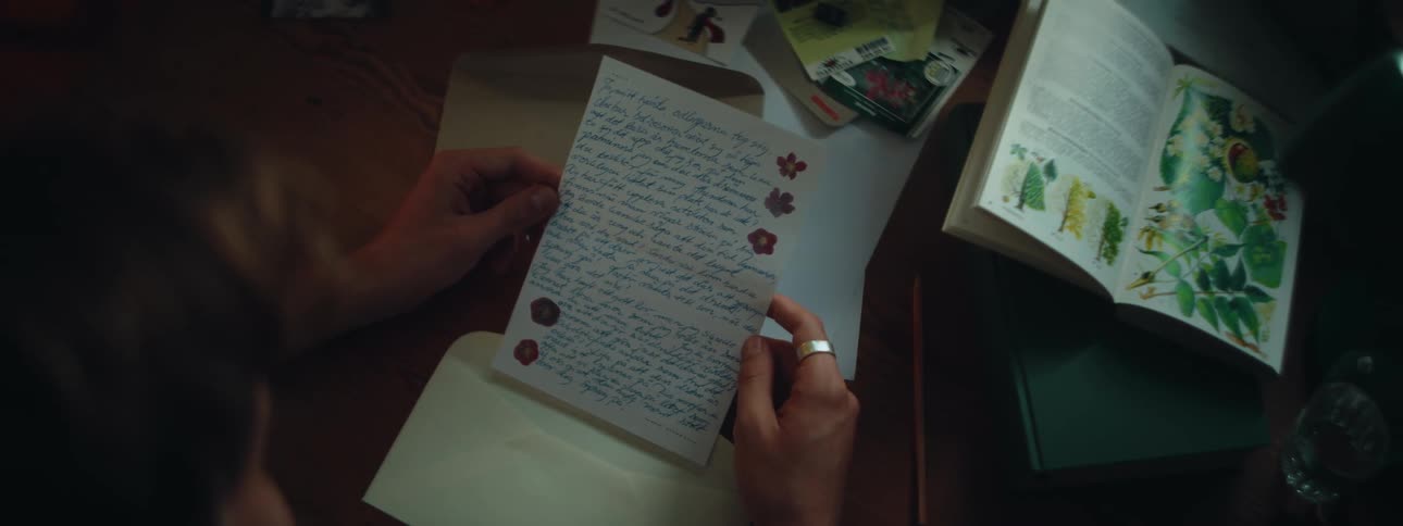 A person is reading a letter and sitting at a table