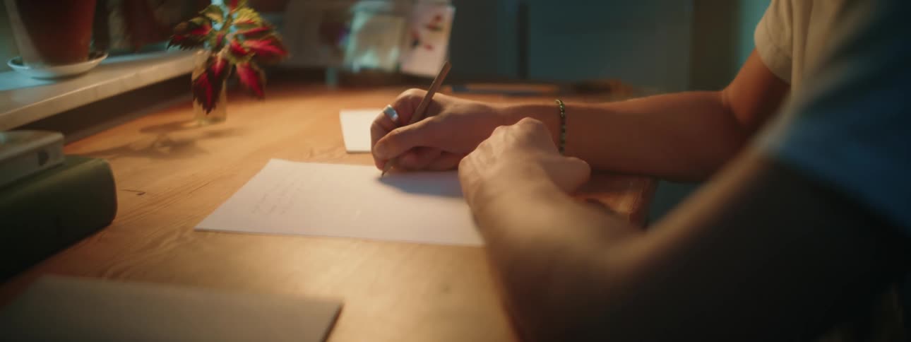 Young man sitting at desk writes on paper