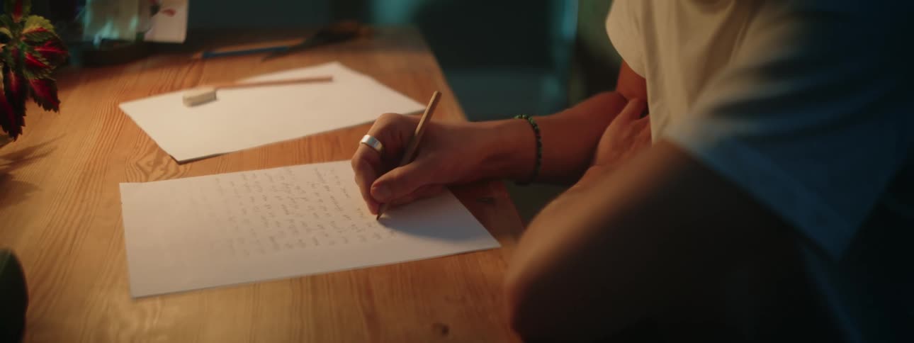 A man is writing with a pencil