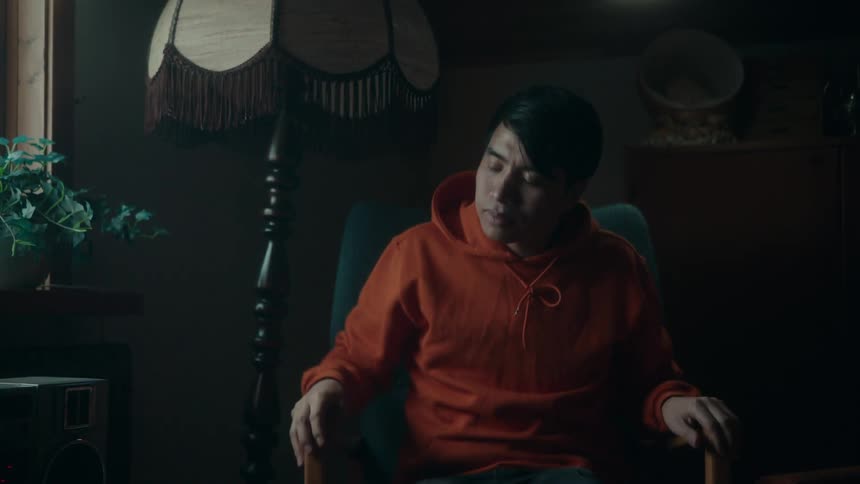 The view is of an asian man that is sitting down inside of his home